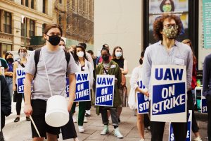 学生在面具，社会疏远，戴着迹象说明罢工